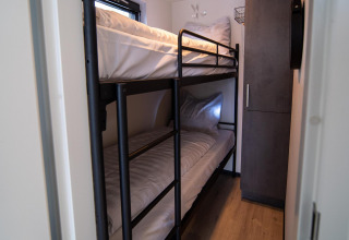 Dormitorio estrecho con literas y armario en Houseboat Heeg en Marina Heeg, Países Bajos, visto desde la puerta.
