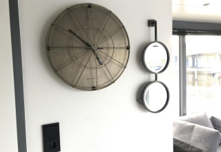 Pared con reloj moderno y dos espejos en el Houseboat Heeg ubicado en Marina Heeg, Países Bajos.