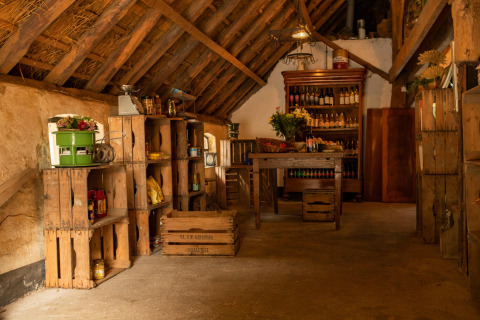 Interior rústico de una tienda de granja en Feather Down Landgoed Volenbeek con cajas y estantes de madera llenos.