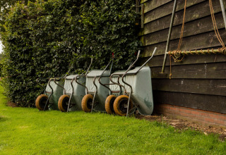 Quatre brouettes alignées près d’un bâtiment en bois et d’une haie à Feather Down Landgoed Volenbeek, Gelderland, Pays-Bas.