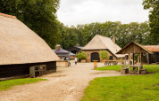 Alojamiento rural con edificios de techo de paja y mesas de picnic en Feather Down Landgoed Volenbeek, Gelderland.