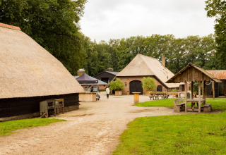 Fattoria vacanze con edifici dal tetto di paglia e tavoli da picnic a Feather Down Landgoed Volenbeek, Gelderland.