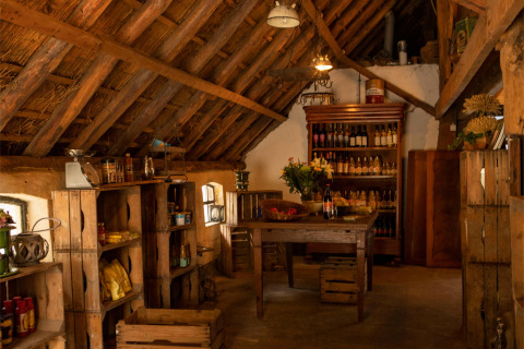 Interior rústico de tienda con estanterías de madera y botellas en Landgoed Volenbeek, Gelderland, Países Bajos.