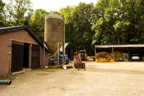 Cortile agricolo con stalla, silo, trattori e fieno a Feather Down Landgoed Volenbeek, Gelderland, Paesi Bassi.