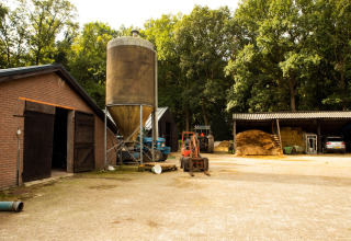 Cortile agricolo con stalla, silo, trattori e fieno a Feather Down Landgoed Volenbeek, Gelderland, Paesi Bassi.