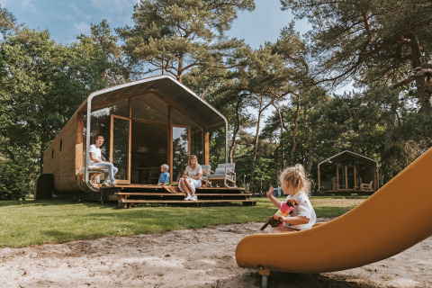 Famille profitant du séjour à la Wikkelhouse XL lodge, enfants jouant sur un toboggan extérieur.
