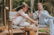 Pareja disfruta de vino y aperitivos en la terraza de Wikkelhouse XL lodge en Beerze Bulten, Países Bajos.