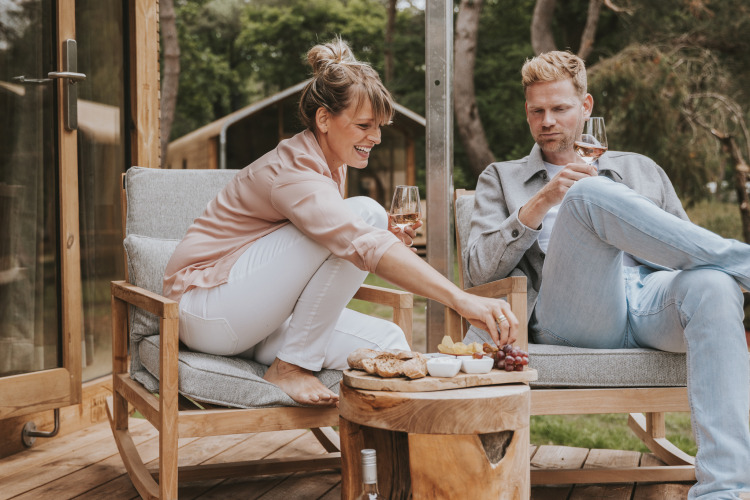 Paar genießt Wein und Snacks auf der Terrasse der Wikkelhouse XL Lodge bei Beerze Bulten, Niederlande.
