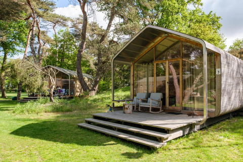 Lodge Wikkelhouse XL à Beerze Bulten, Pays-Bas, entouré d’arbres et d’une pelouse verdoyante.