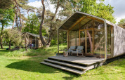Wikkelhouse XL-lodge bij Beerze Bulten in Nederland, te midden van bomen en een groene omgeving.