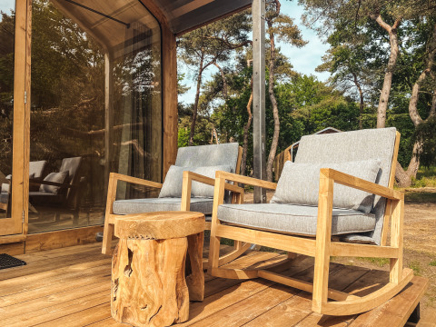 Terraza exterior de Wikkelhouse XL en Beerze Bulten, Países Bajos, con dos mecedoras y mesa de madera.