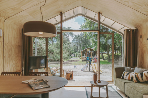 Vista interior de la cabaña Wikkelhouse XL en Beerze Bulten, Países Bajos, con acceso a área de juegos.