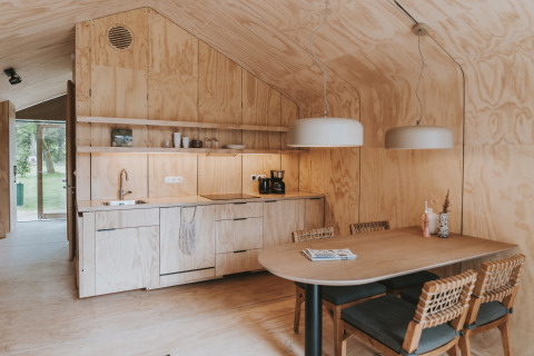 Interior moderno de lodge en Wikkelhouse XL, Beerze Bulten, Países Bajos, con paredes de madera y comedor.