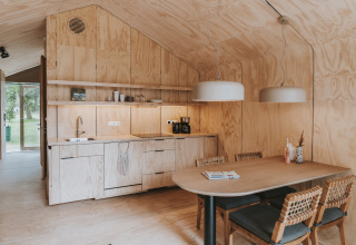 Interni moderni della lodge Wikkelhouse XL a Beerze Bulten, Paesi Bassi, con pareti in legno e zona pranzo.