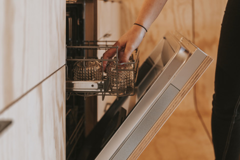 Personne plaçant des verres dans un lave-vaisselle ouvert à Wikkelhouse XL à Beerze Bulten, Pays-Bas.