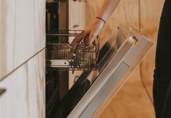 Persoon laadt glazen in een open vaatwasser bij Wikkelhouse XL in Beerze Bulten, Nederland.