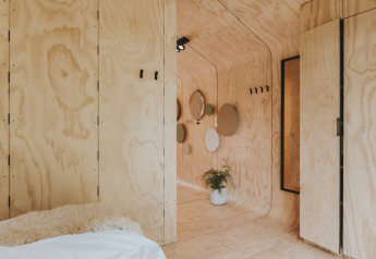 Interno di Wikkelhouse XL a Beerze Bulten, Paesi Bassi, con compensato chiaro e arredo minimalista.