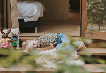 Un bambino sorridente sdraiato su una coperta davanti a Wikkelhouse XL lodge a Beerze Bulten, Paesi Bassi.