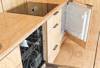 Cocina moderna con lavavajillas y frigorífico abiertos en Wikkelhouse XL de Beerze Bulten, Países Bajos.