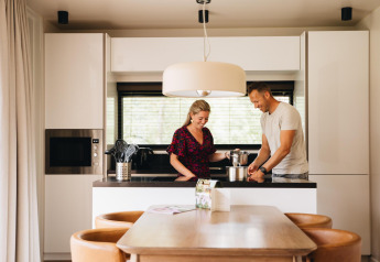 Koppel kookt samen in de moderne keuken van Hill Lodge in Beerze Bulten, Nederland, met eetgedeelte.