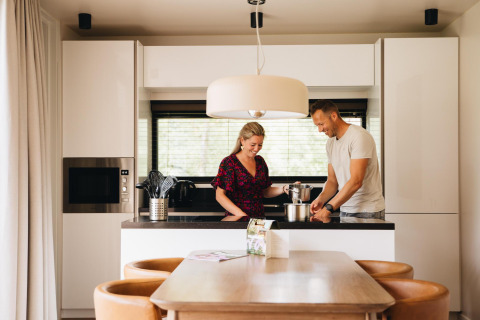 Una pareja cocina junta en la moderna cocina de Hill Lodge en Beerze Bulten, Países Bajos, con área de comedor.
