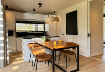 Moderne keuken en eetruimte in Hill Lodge aan Beerze Bulten, Nederland, met vier stoelen en sap.