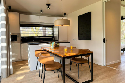 Moderne Küche und Essbereich im Hill Lodge bei Beerze Bulten, Niederlande, mit vier Stühlen und Saft.