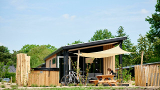Tiny house Sand Lodge Jacuzzi con bicicletas y mesa de picnic en Holiday Park De IJsvogel, Países Bajos, rodeado de naturaleza.