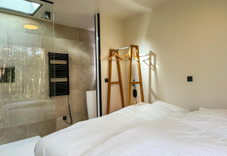 Moderne slaapkamer in Hill Lodge bij Beerze Bulten, Nederland, met tweepersoonsbed en glazen douche.