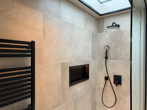 Modern shower with black fixtures, wall-mounted niche, and skylight at Hill Lodge in Beerze Bulten, Netherlands.