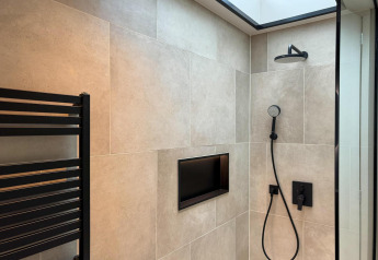 Moderne douche met zwarte kranen, wandnis en dakraam in Hill Lodge bij Beerze Bulten, Nederland.