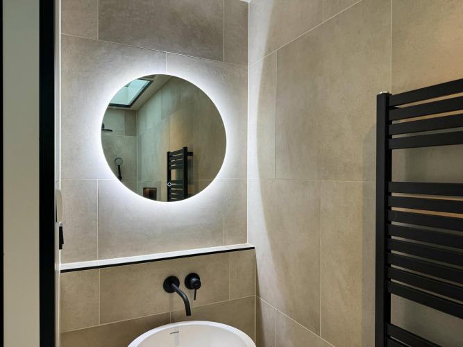 Modern bathroom sink with round backlit mirror at Hill Lodge in Beerze Bulten, the Netherlands.
