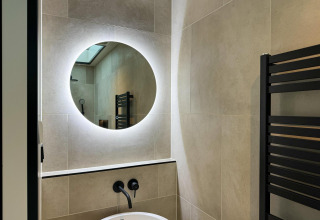 Modernes Badezimmer mit rundem, hinterleuchtetem Spiegel im Hill Lodge bei Beerze Bulten in den Niederlanden.