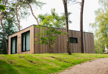 Hill Lodge à Beerze Bulten aux Pays-Bas, cabane moderne en bois entourée d'arbres et de nature verdoyante.