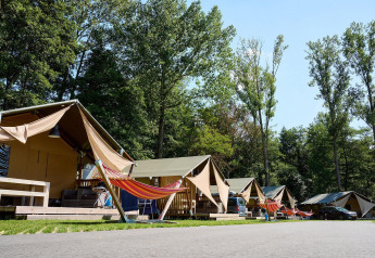 Tiendas safari con hamacas en Villatent Nomad, Recreatieoord Wilhelm Tell, Bélgica, rodeadas de árboles