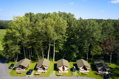 Vista aérea de tiendas safari Villatent Nomad en Recreatieoord Wilhelm Tell, Bélgica, rodeadas de árboles.