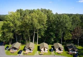 Vista aérea de tiendas safari Villatent Nomad en Recreatieoord Wilhelm Tell, Bélgica, rodeadas de árboles.