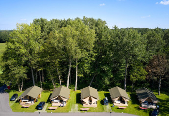 Vista aérea de tiendas safari Villatent Nomad en Recreatieoord Wilhelm Tell, Bélgica, rodeadas de árboles.