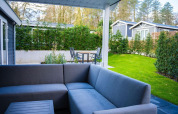 Moderne udendørs lounge med gråt sofamøbel på terrasse ved Heuvelrug Cottage, De Thijmse Berg, Holland.