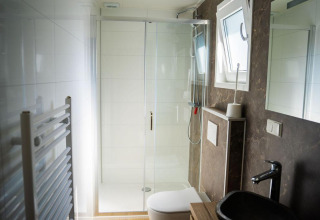 Baño moderno en Heuvelrug Cottage, De Thijmse Berg, con ducha, inodoro, lavabo y ventana en los Países Bajos.