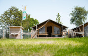Safaritent Villatent Compact met privé sanitair, hangmatten en groen grasveld op een zonnige dag