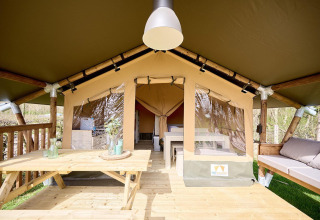Tienda safari Villatent Compact + sanitario, terraza de madera con mesa y vista a la naturaleza.
