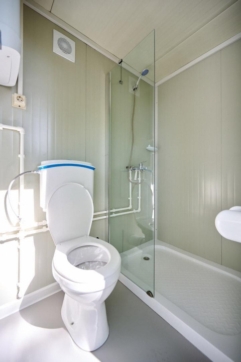 Baño moderno con inodoro y ducha en la tienda safari Villatent Compact con baño privado y sanitario.