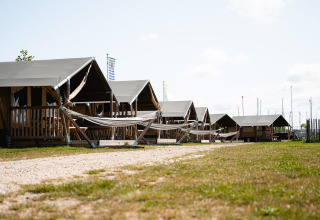 Safari tenten Villatent Compact met sanitaire voorzieningen en hangmatten op een zonnig grasveld.