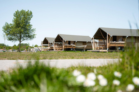 Safaritenten Villatent Compact met eigen sanitair, groene omgeving en blauwe lucht op de achtergrond.