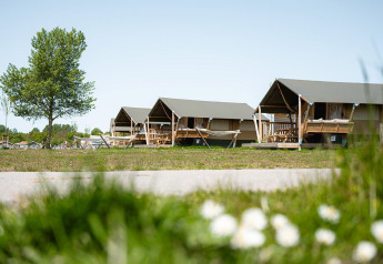 Safari tents Villatent Compact with private sanitary facilities, green area, and clear sky in the background.