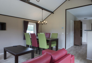 Zona pranzo moderna in una casa immersa nella natura con sedie colorate, tavolo scuro e arredo accogliente.