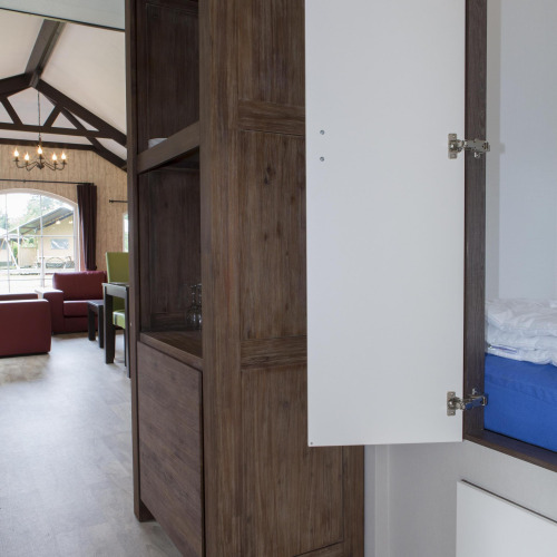 Innenraum eines Naturhauses mit offenem Schrank, Sofas und großem Fenster mit Blick nach draußen.