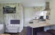Intérieur de lodge moderne avec cuisine ouverte, table et salon à Veluwecamping De Pampel, Pays-Bas.