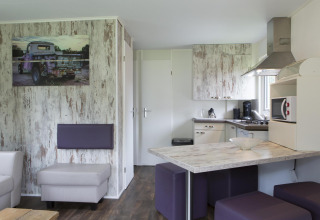 Moderne lodge med åbent køkken, spiseområde og stue i skandinavisk stil på Veluwecamping De Pampel.